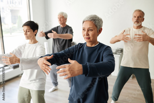 Medium full shot of senior male and female qigong class participants practicing tree pose for meditation