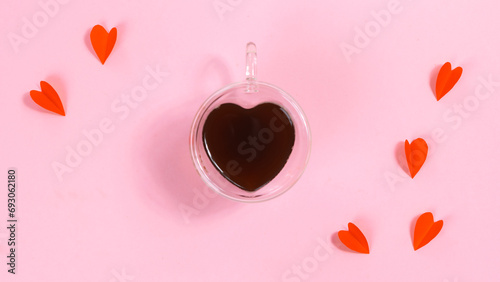 Heart-shaped cup is filled with coffee near paper butterfly hearts. The concept of love, valentine's holiday or favorite drinks.