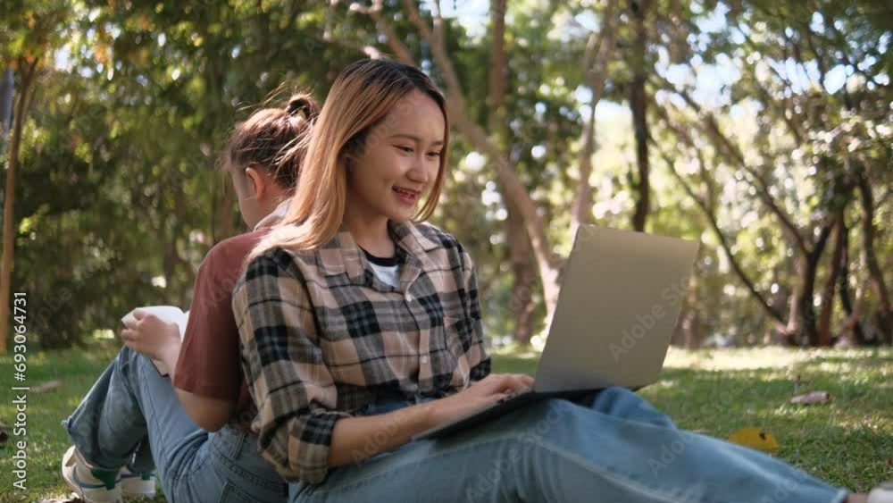 Two female students working and learning together for exams sitting on University campus grass Two female students working and learning together for exams sitting on University campus grass