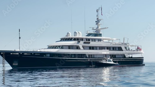Mega yacht and a small boat in a sea near Hydra, Greece.