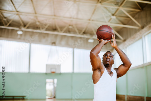 Young man shooting basketball jump shot in indoor court photo