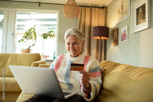 Senior woman paying online expenses with debit card at home photo