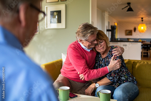 Senior Couple Sharing Comforting Embrace in a Living Room with Therapist photo