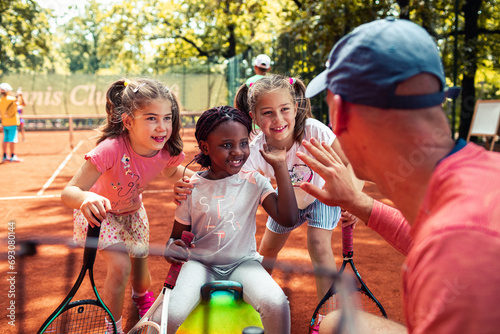 Tennis coach giving tips to little girls during practice photo
