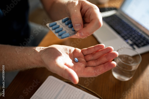Close up male hands holding pill with medication packaging photo