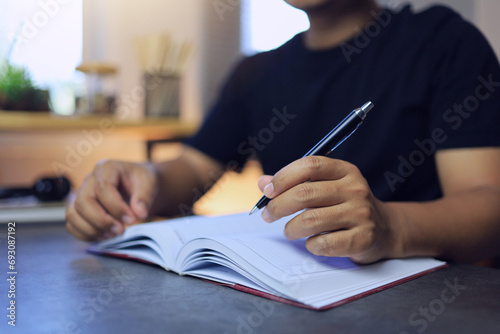 A man uses a pen to write on a notebook to write a memo or compose a song and review goals or plan topics for the next year photo