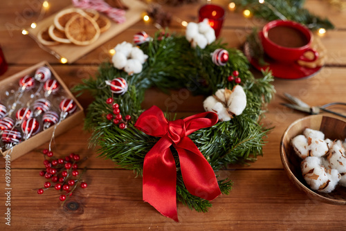 winter holidays, diy and hobby concept - close up of christmas fir wreath making stuff, decorations and hot chocolate on wooden table