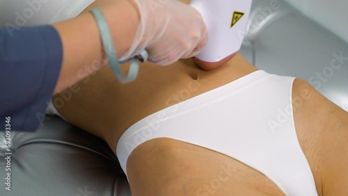 Woman with fit body getting laser hair removal procedure at beauty clinic photo