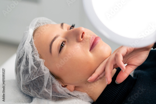 close-up of a satisfied face of a female client in a beauty salon looking in the mirror enjoying the result of a cosmetic procedure
