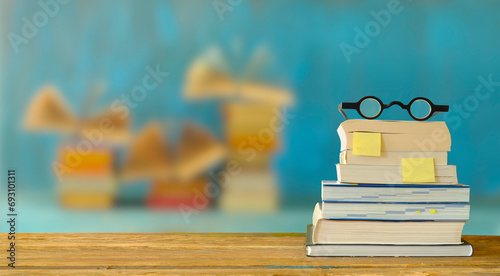 Obraz na plátně stack of books, booksmarks and spectacles, blurred open books in the background