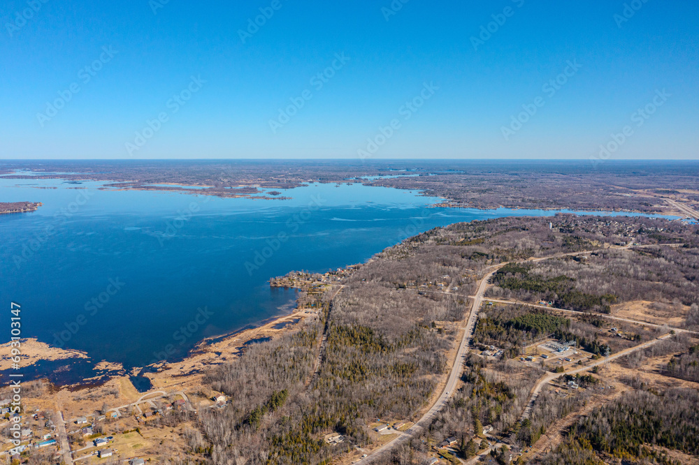 Expansive aerial views over Tay Township, Simcoe County, Ontario, capture the grandeur of the Canadian landscape. From the shimmering waters reflecting the sun's glare to the sprawling patches.