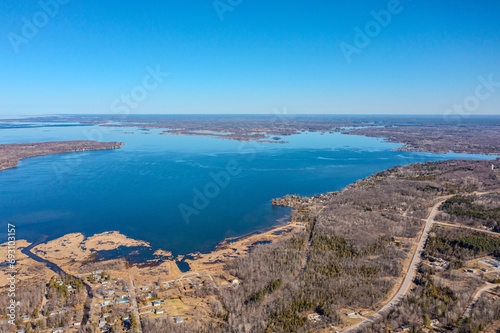 Expansive aerial views over Tay Township, Simcoe County, Ontario, capture the grandeur of the Canadian landscape. From the shimmering waters reflecting the sun's glare to the sprawling patches.