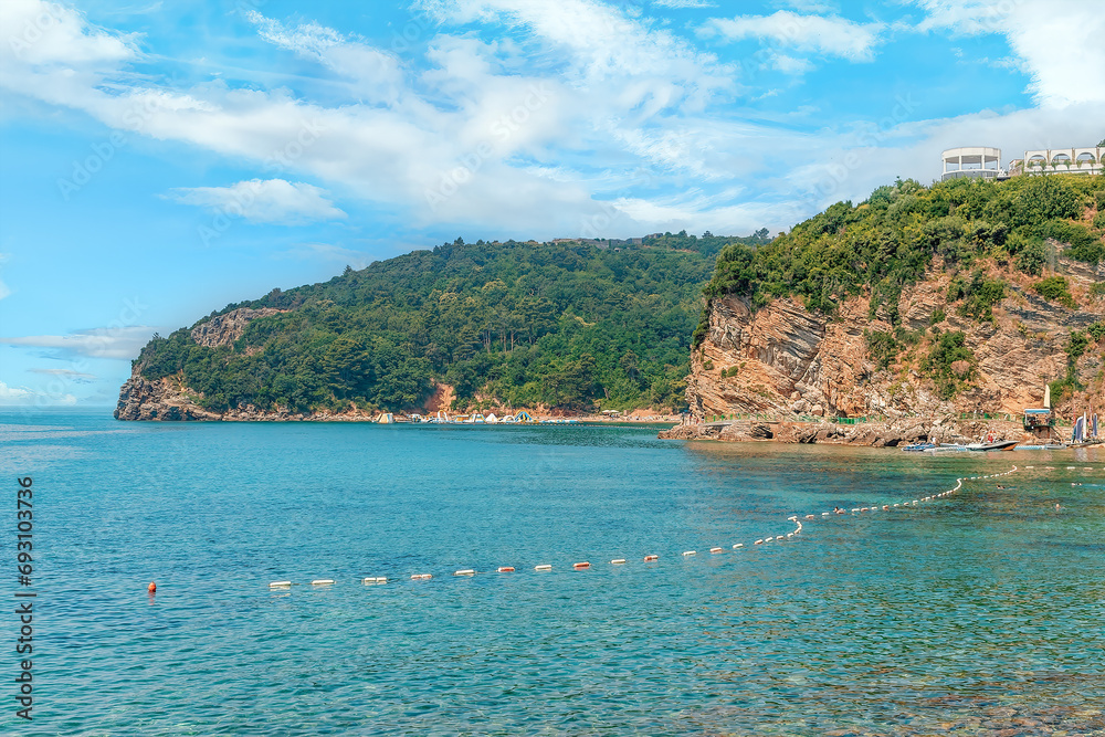 View from the Adriatic Sea to Mogren Beach in Budva, Montenegro. Amazing seascape with layered rocks and forested mountains on the seashore View from the Adriatic Sea to Mogren Beach in Budva, Montenegro. Amazing seascape with layered rocks and forested mountains on the seashore