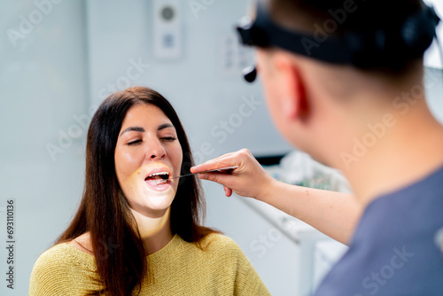 the ENT doctor examines the patient in the office of the clinic, checks the oral and nasal cavity and ear canals with professional instruments photo