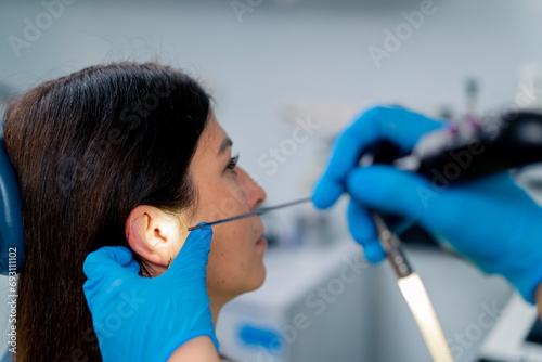 An ENT doctor performs an endoscopy procedure on a patient's ear in a clinic holding a professional device in his hand