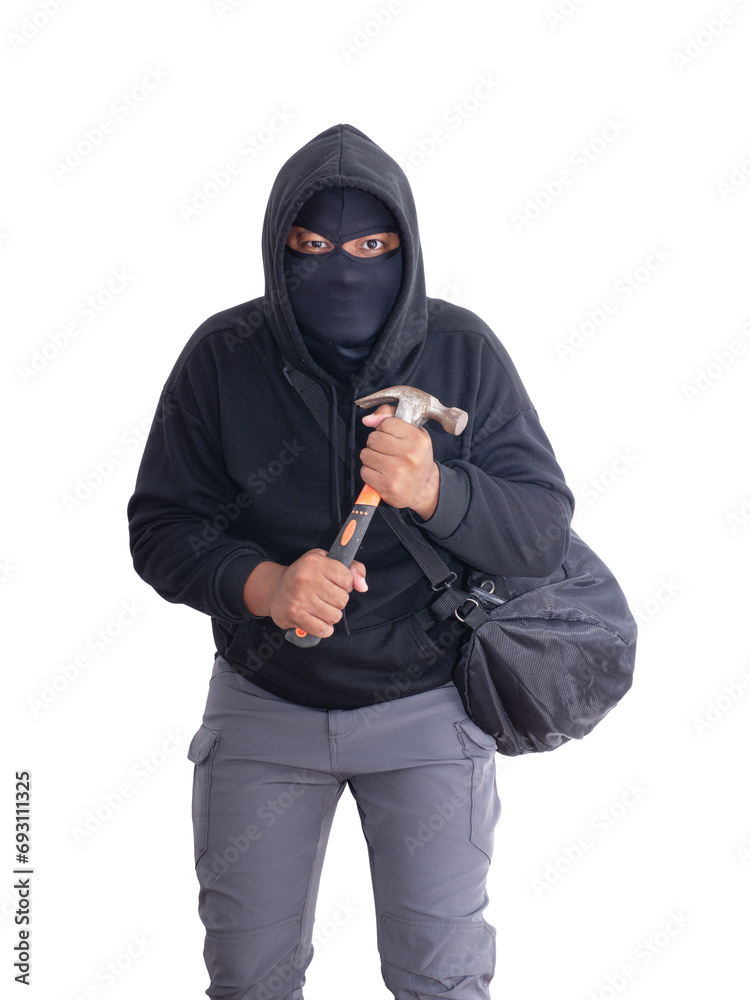 An unidentified male criminal wearing a black hoodie and covering his face, holding a hammer and carrying a large black bag. On a white background with cliping path. Thief.weapon, crime.