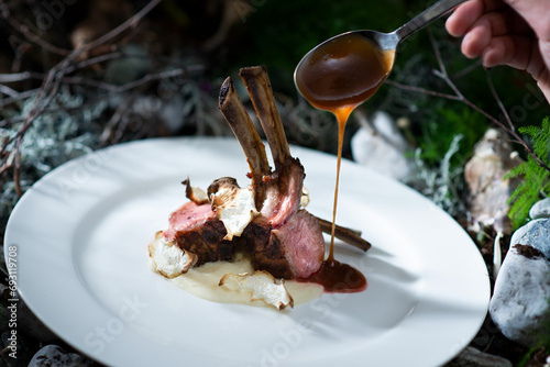 Carrè di agnello con funghi e purè. Food gourmet presentazione su piatto con cucchiaio che gocciola salsa