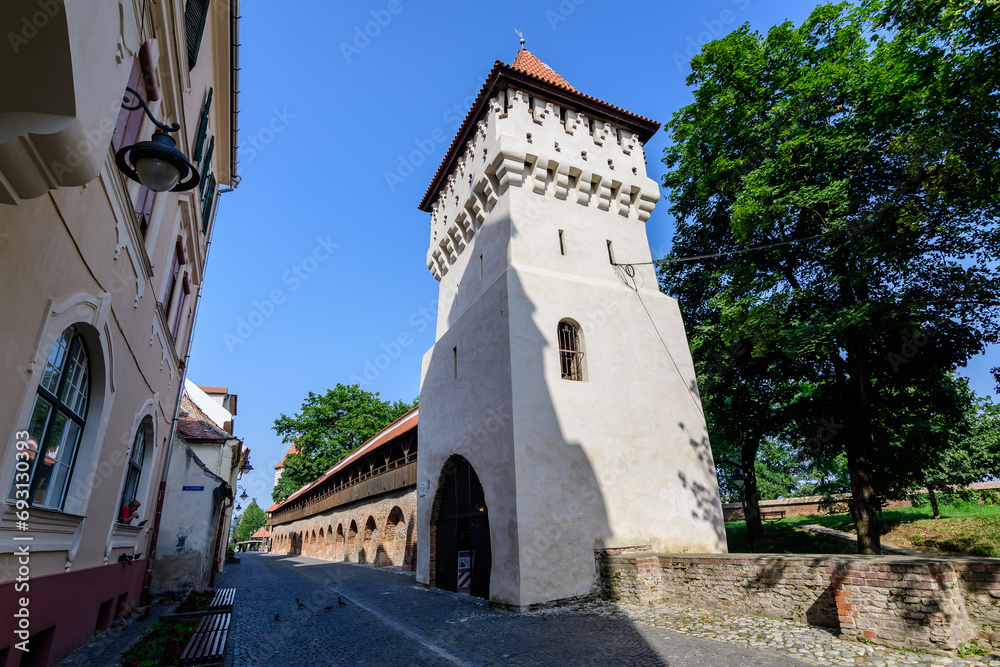 Large old white painted stone tower in the historical center of the Sibiu city, near Citadel Street and Park (Strada si Parcul Cetatii), in Transylvania (Transilvania) region of Romania, in summer.