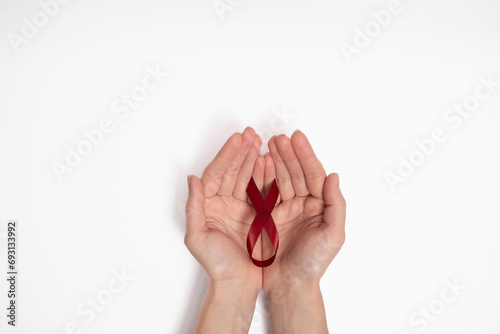 Woman holding red ribbon as symbol of World Cancer Day, on white background, breast cancer awareness sign.