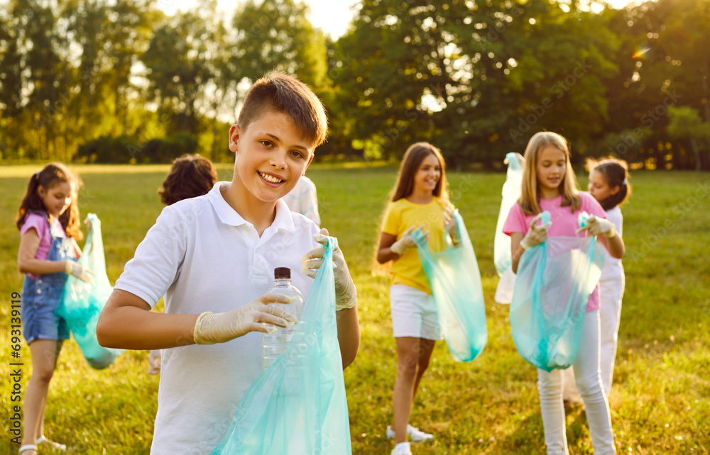 Portrait of preteen boy collecting plastic trash during summer cleanup ...