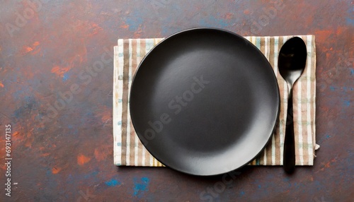 Top view on dark blue background empty round white plate on tablecloth for food	
