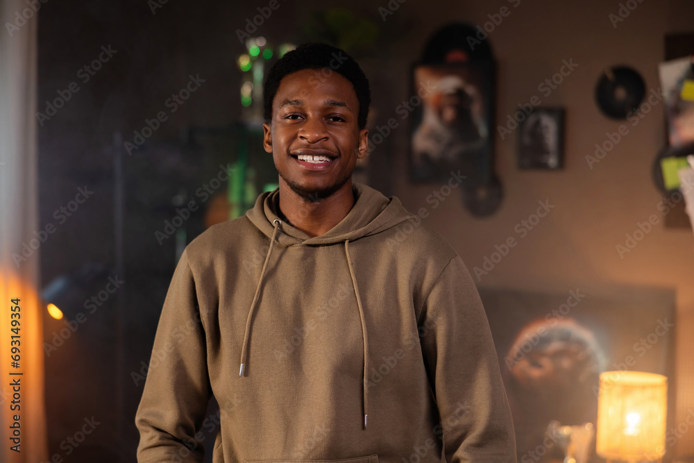 Portrait of delighhted african american man wearing casual hoodie standing in the cozy beautiful living room smiling looking at camera. Successful freelnacerworks from home online. Portrait of delighhted african american man wearing casual hoodie standing in the cozy beautiful living room smiling looking at camera. Successful freelnacerworks from home online.