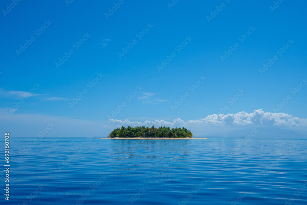 A small island in Fiji on a clear blue sky day in the South Pacific