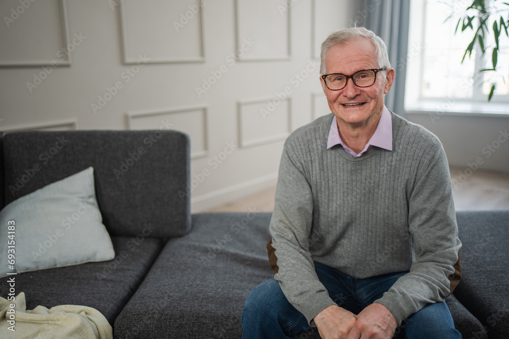 Fototapeta premium Portrait of confident stylish European middle aged senior man at home. Older mature 70s man smiling. Happy attractive senior grandfather looking camera close up face headshot portrait. Happy people
