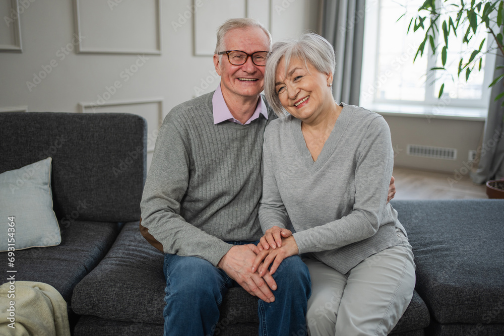 Senior adult mature couple hugging at home. Mid age old husband and wife embracing with tenderness love enjoying sweet bonding wellbeing. Grandmother grandfather together. Family moment love and care Senior adult mature couple hugging at home. Mid age old husband and wife embracing with tenderness love enjoying sweet bonding wellbeing. Grandmother grandfather together. Family moment love and care