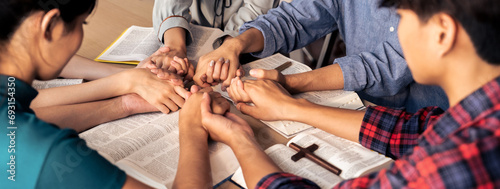 Cropped image of diversity people hand praying together at wooden church on bible book while hold hand together with believe. Concept of hope, religion, faith, god blessing concept. Burgeoning.