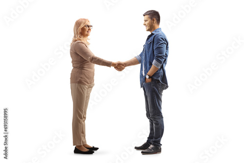 Full length profile shot of middle aged woman and a younger man shaking hands