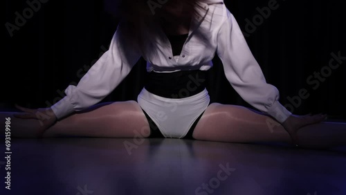 A sexy scene with a young girl. Model dancing in front of the camera, brunette woman. Gymnast, dancer, in the dark. Indoor night shooting. Erotic and dynamic dance, teaches attractive movements