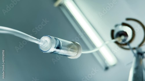 Drip chamber of a IV with dropper bottle on a stand. Intravenous injections, medical care in a clinic. Recovering patient. Bottom up. Wide angle view. Closeup. Vertical video photo