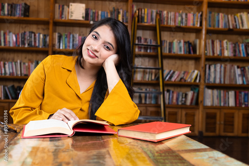 A beautiful young girl business woman or student working or studying in school or collage library or in corporate office sitting with books