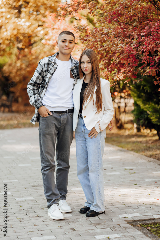 Vertical photo of two teenage friends dressed in casual clothes standing next to each other against a background of nature. Best school friends are ready to overcome anything to achieve the goal. Vertical photo of two teenage friends dressed in casual clothes standing next to each other against a background of nature. Best school friends are ready to overcome anything to achieve the goal.
