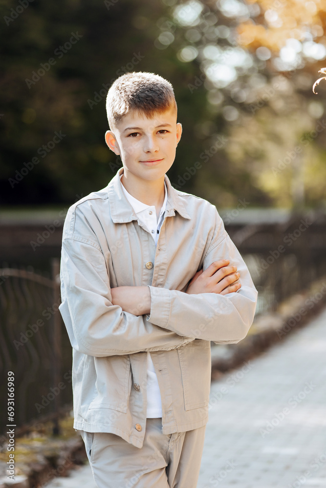 Vertical close-up portrait of a teenager in casual clothes. Happy smiling teenager in autumn park in sunlight. A beautiful child looks at the camera in nature. Vertical close-up portrait of a teenager in casual clothes. Happy smiling teenager in autumn park in sunlight. A beautiful child looks at the camera in nature.