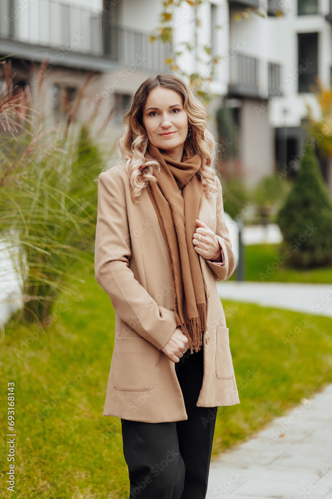 Fototapeta premium Vertical photo. Beautiful carefree young girl in casual clothes. Portrait of a beautiful girl against the background of nature with a blurred background.