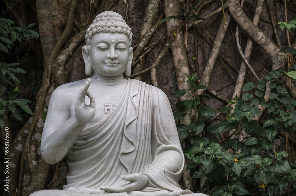 Statue of Buddha Marble Mountains Danang, Vietnam, Asia.  The statue is set against dense, tropical foliage