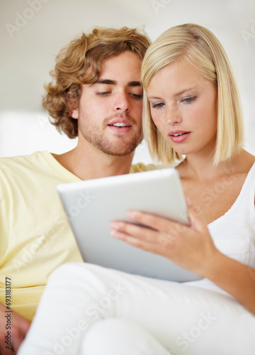 Research, tablet and young couple on sofa browse on social media or internet at apartment. Happy, digital technology and man and woman from Australia relax and scroll on website in lounge at home.