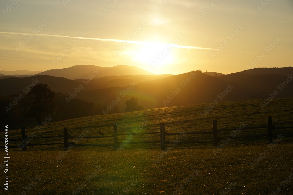 Idyllic colorful sunset scenery at Hochroterd in Breitenfurt in autumn. View to green meadow and rolling hills in the background in Lower Austria. Idyllic colorful sunset scenery at Hochroterd in Breitenfurt in autumn. View to green meadow and rolling hills in the background in Lower Austria.