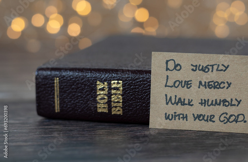 Do justly, love mercy, walk humbly with your God, handwritten biblical quote, Micah 6:8 and holy bible with bokeh background. Christian biblical concept of humility and obedience to Jesus Christ. photo
