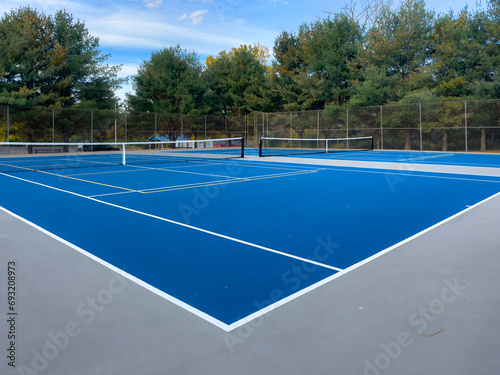 Close up photo of a outdoor blue tennis court with white lines combined with yellow  gold  pickleball lines. 