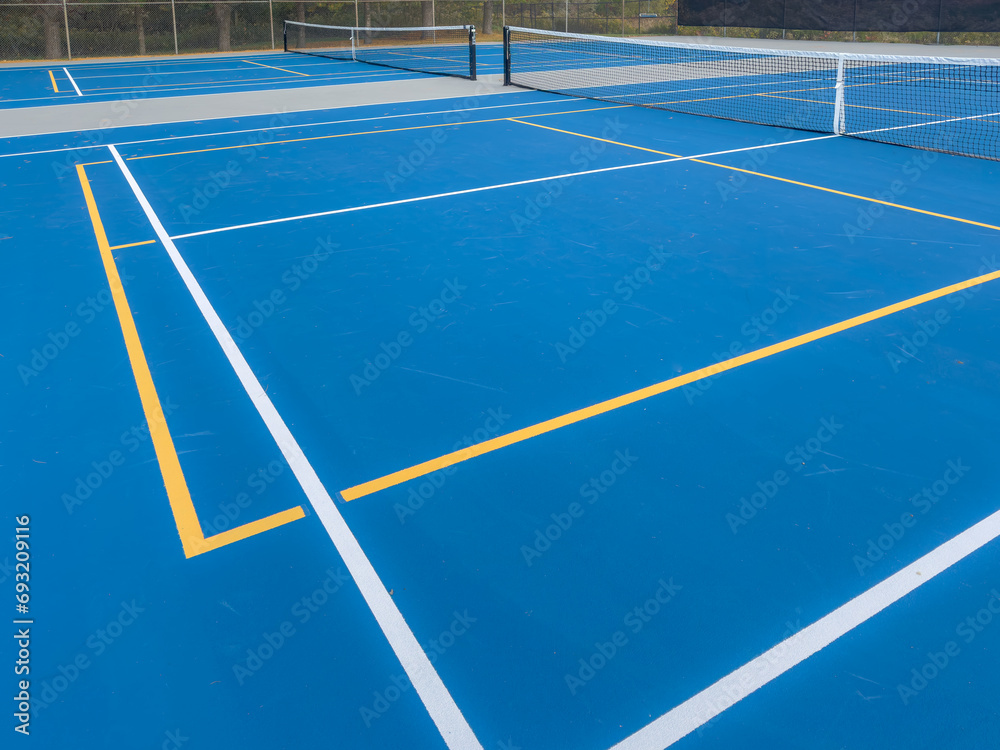 Close up photo of a outdoor blue tennis court with white lines combined with yellow, gold, pickleball lines.	 - obrazy, fototapety, plakaty 