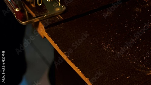 Jigsaw cuts a board. Electric jigsaw cuts a wooden slab. A piece of furniture is cut with a saw in a carpentry workshop. Assembling furniture in a factory. Carpenter works with wood. Professional tool