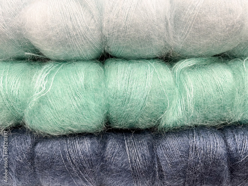 Pile of colorful fluffy skeins for knitting and crocheting. Blue and green skeins of wool yarn. Background for content related to hobbies, handmade and craft. photo