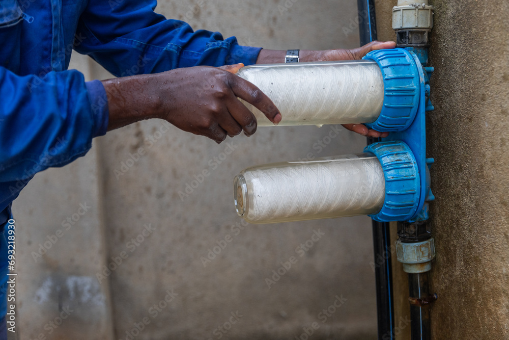 African plumber replaces the water filters. Clean water concept - obrazy, fototapety, plakaty 