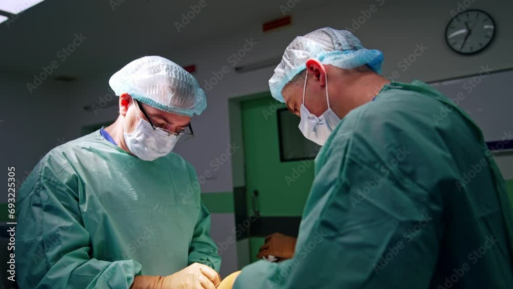 Male Caucasian doctors using metal tools at operation. Assistant passes the instruments and materials to the surgeons. Male Caucasian doctors using metal tools at operation. Assistant passes the instruments and materials to the surgeons.