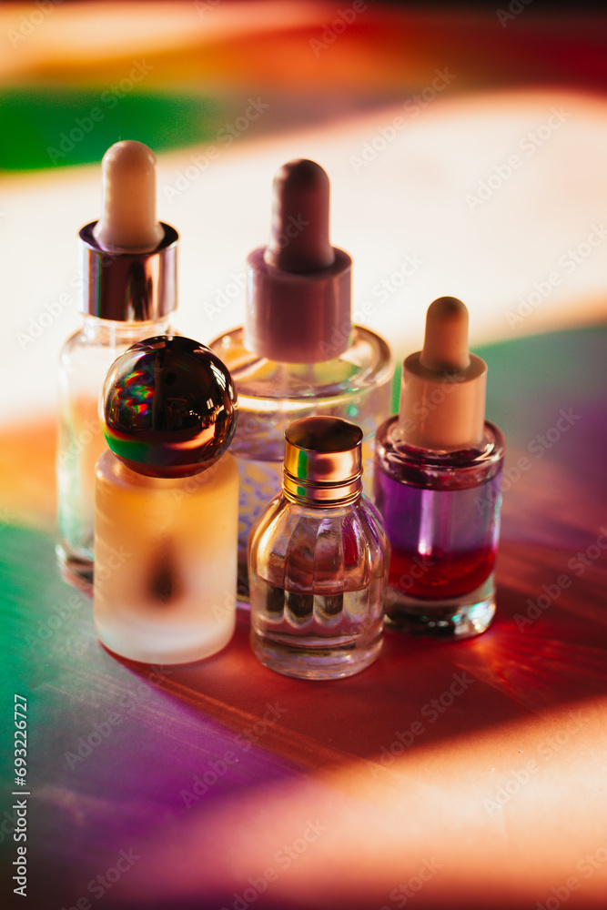 Set of small cosmetic pipette bottles on colorful rainbow shadows. Face, body oil products. Moisturizer facial cosmetic on a table. Beauty, beautician Set of small cosmetic pipette bottles on colorful rainbow shadows. Face, body oil products. Moisturizer facial cosmetic on a table. Beauty, beautician