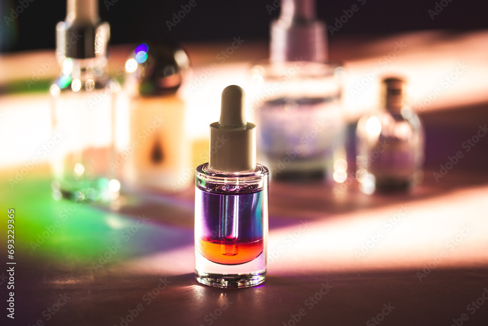 Naklejka premium Glass container with red violet liquid. Two-phase cuticle remove oil. Beautician products on a cosmetic table. Self care tools and products in shadow.