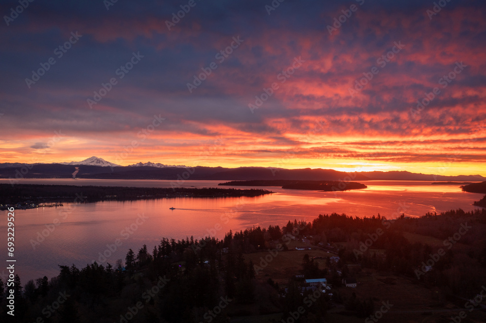 Ferryboat crossing Hale Pass from Lummi Island to Gooseberry Point during a spectacular sunrise.  Bellingham Bay and Mt. Baker can be seen in the background. Dramatic clouds make this image special.